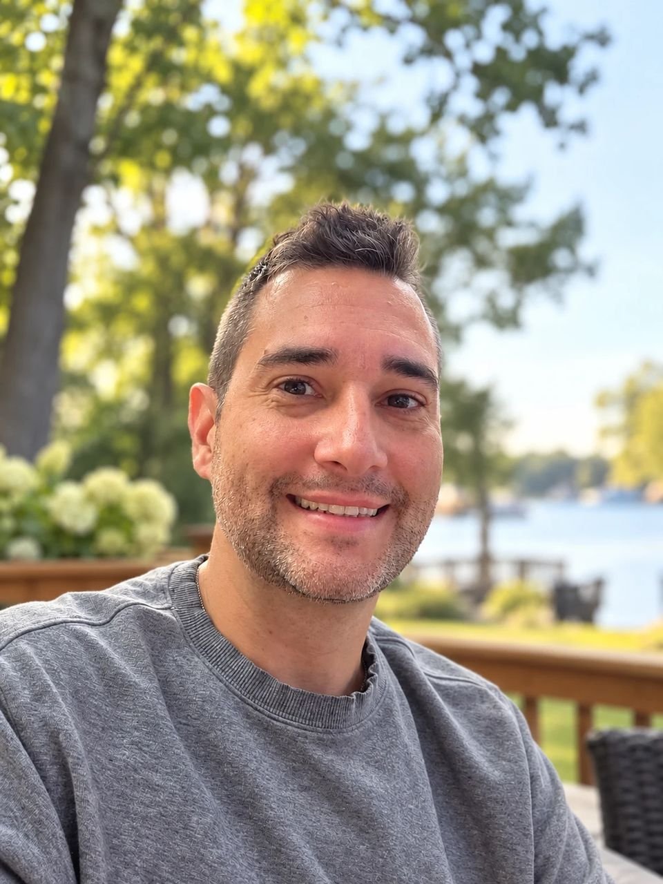 Dave Birnie smiling outdoors by a lake